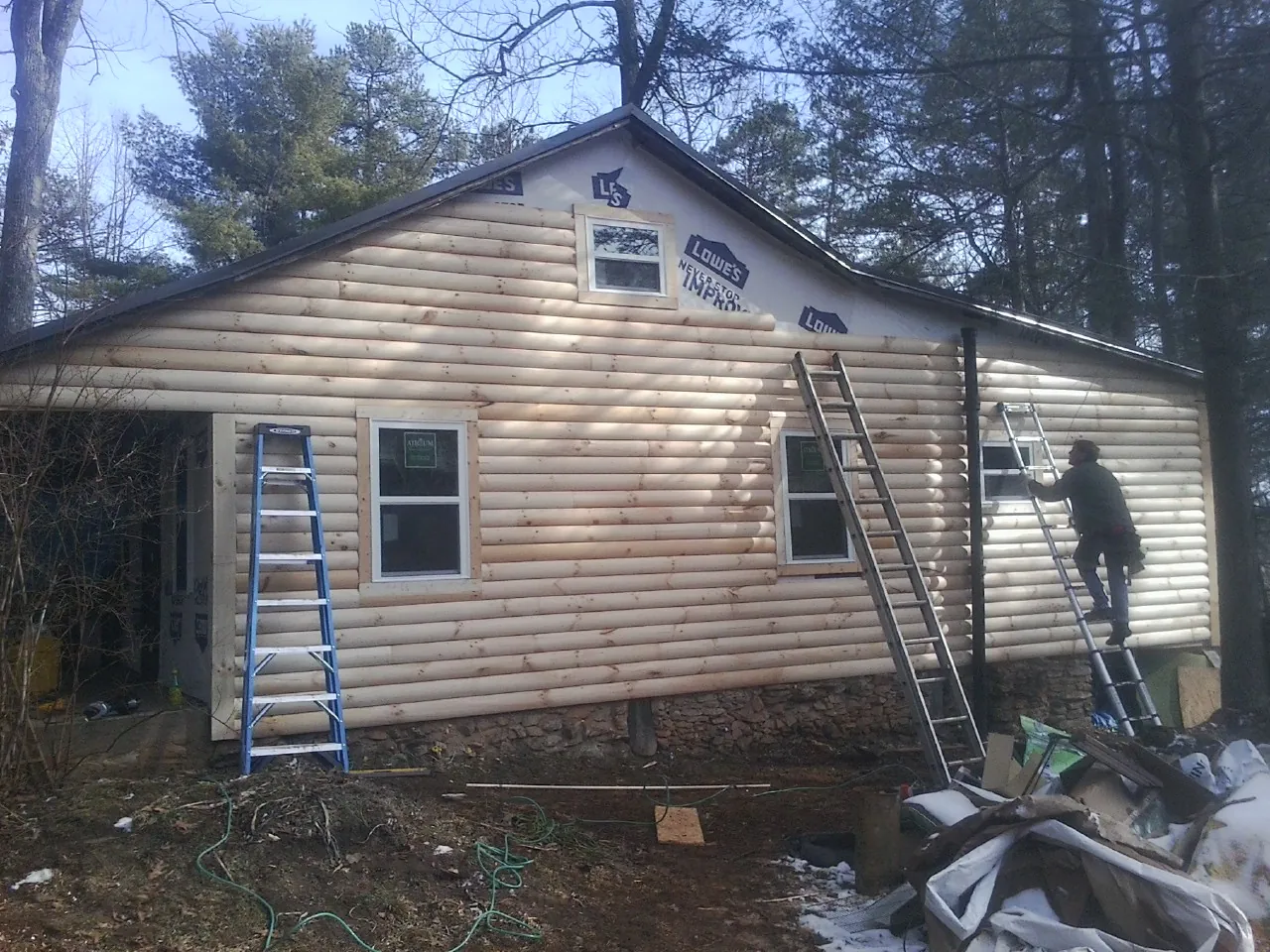 Ladders set against fresh log siding during an exterior remodel in North Charleston