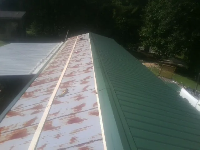 Old rusted panels beside newly installed green metal roofing — Wind Damage Roof Repair by Roofing Brothers in North Charleston