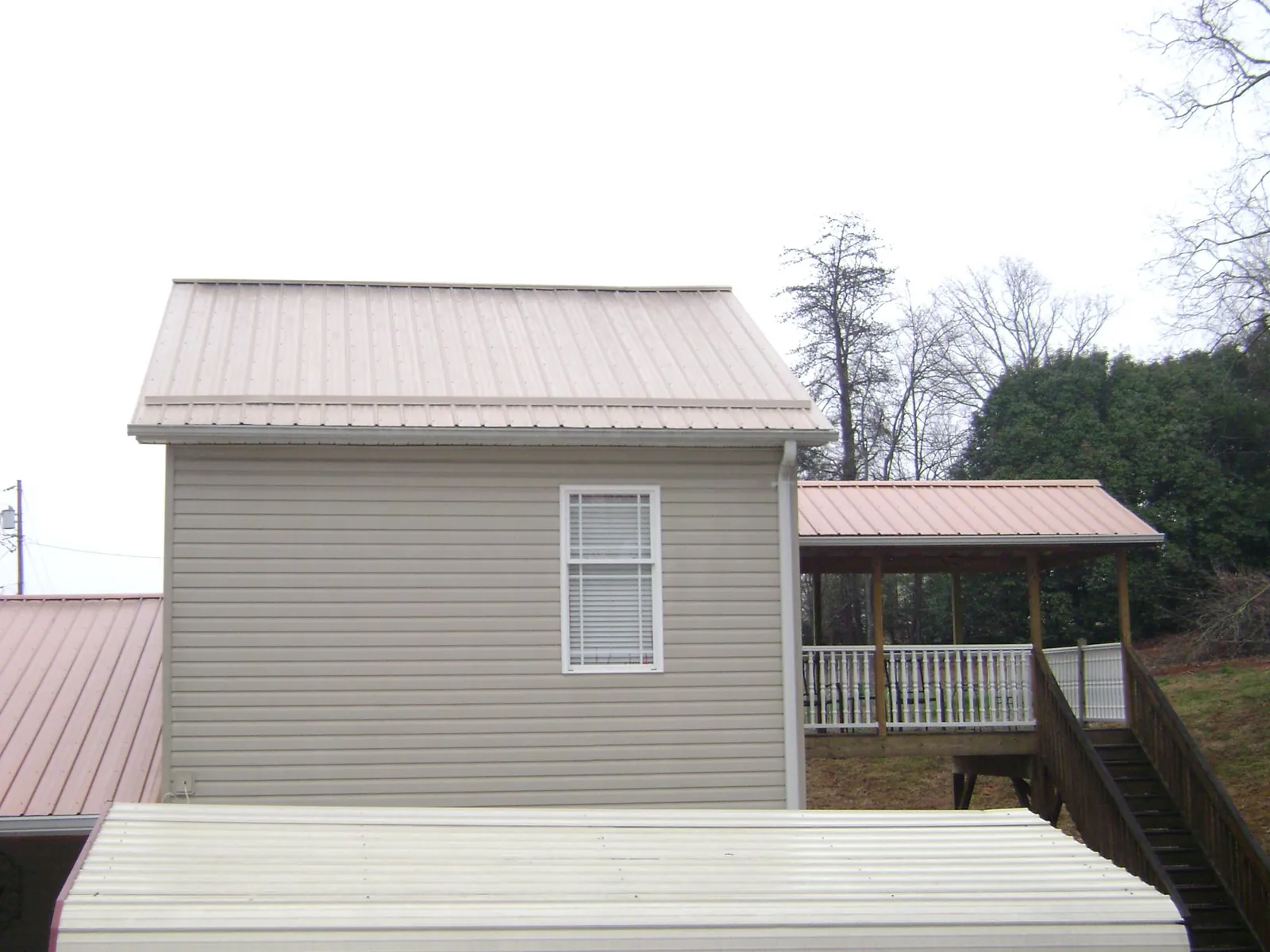 Tan metal roofs on a two story addition and attached porch, from a Roof Replacement job in North Charleston