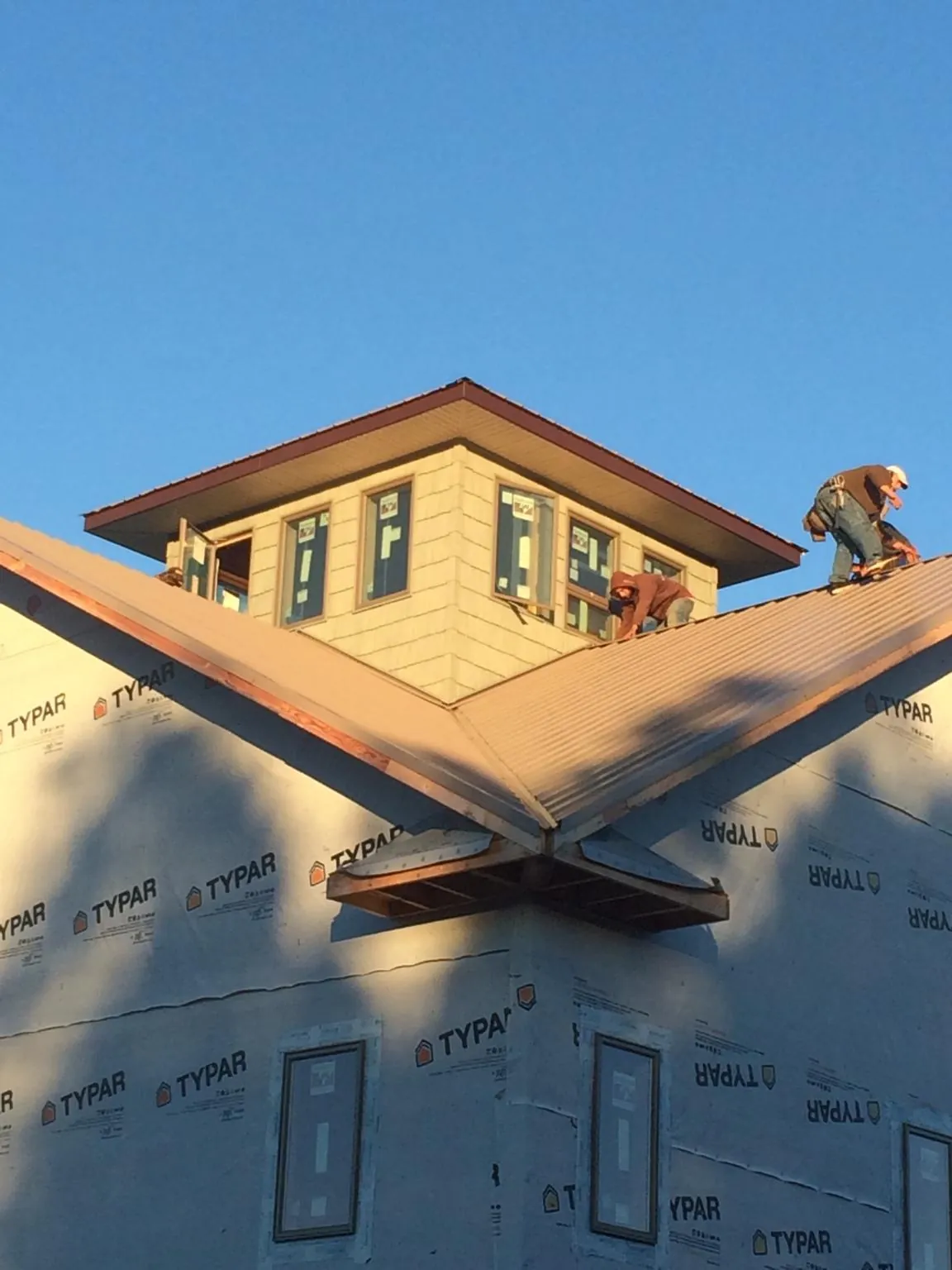 Roofers working around a rooftop cupola on a new metal roof at sunset — Roof Waterproofing in North Charleston by Roofing Brothers
